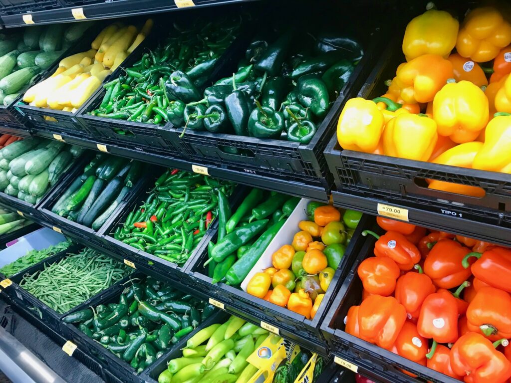 色鮮やかで新鮮な野菜が美しく並ぶ小売店の売場作り。大手の低価格競争に巻き込まれないために、中小小売店が専門性やこだわり、体験価値の差別化を追求する品揃えと、売場演出の重要性を示す実例イメージ。