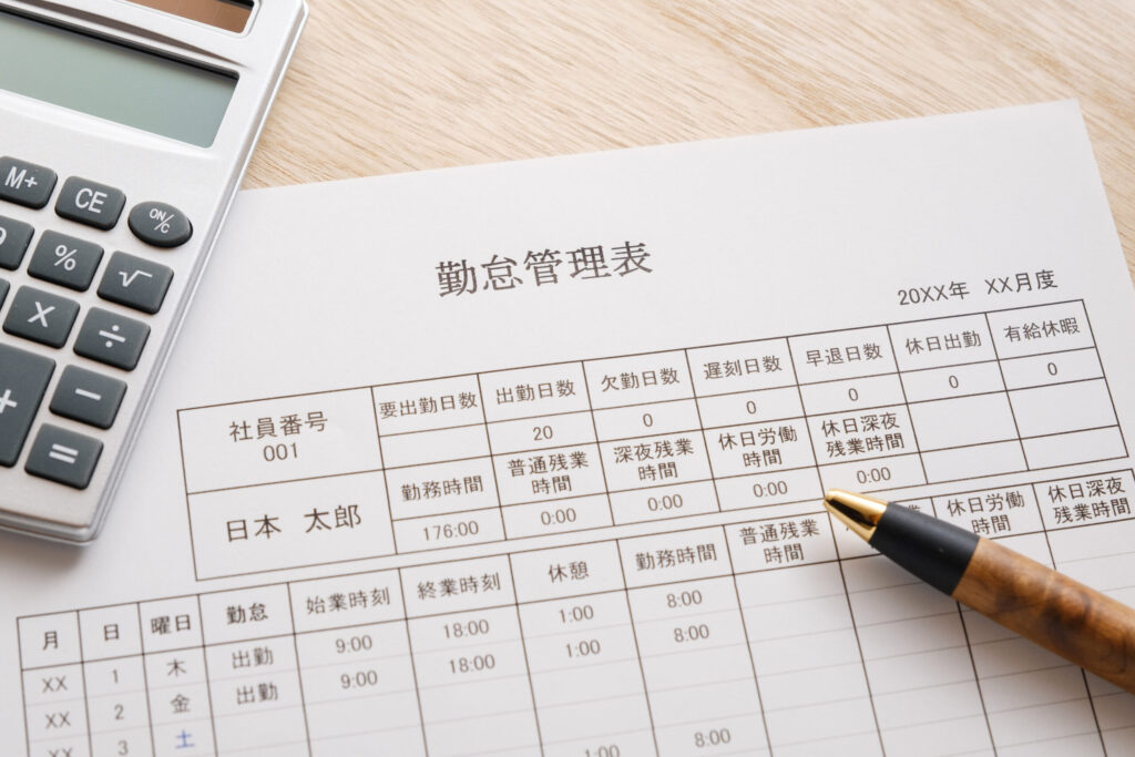 電卓、ペン、詳細な勤怠管理表。出勤日数や残業時間を精緻に把握し、人件費削減と業務効率化を両立。店長に必要なマネジメント知識として、知識不足による労務リスクを未然に防ぎます。実務と評価を連動させ、現場力を最大化する労務管理のプロのイメージ