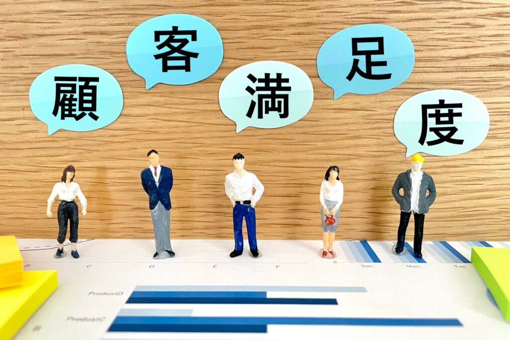 「顧客満足度」の吹き出しと並ぶ人物ミニチュアの画像。店舗経営で不可欠なCS向上やリピーター獲得の戦略を象徴しています。飲食・小売店の店長やオーナーが直面する売上アップの課題に対し、顧客心理を捉えた接客やサービス改善のヒントを専門的に解説。