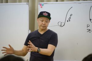 ホワイトボードの前で熱弁を振るう佐藤勝人氏。店舗経営者へリーダーシップの本質と人手不足を解決する仕組み作り、スタッフが自ら考えて動く組織への視点転換を直接指導するセミナー風景。専門性と信頼性を象徴する実践的教育の様子。