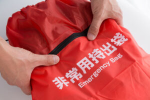 店舗の非常持出袋を確認する経営者。新年度の初動対応を確実にするため、BCPの棚卸しと併せて備品を再点検。新入社員に安心感を与え、人命最優先の経営理念を現場に浸透させるための、経営者が今すぐ実践すべき具体的な準備風景。