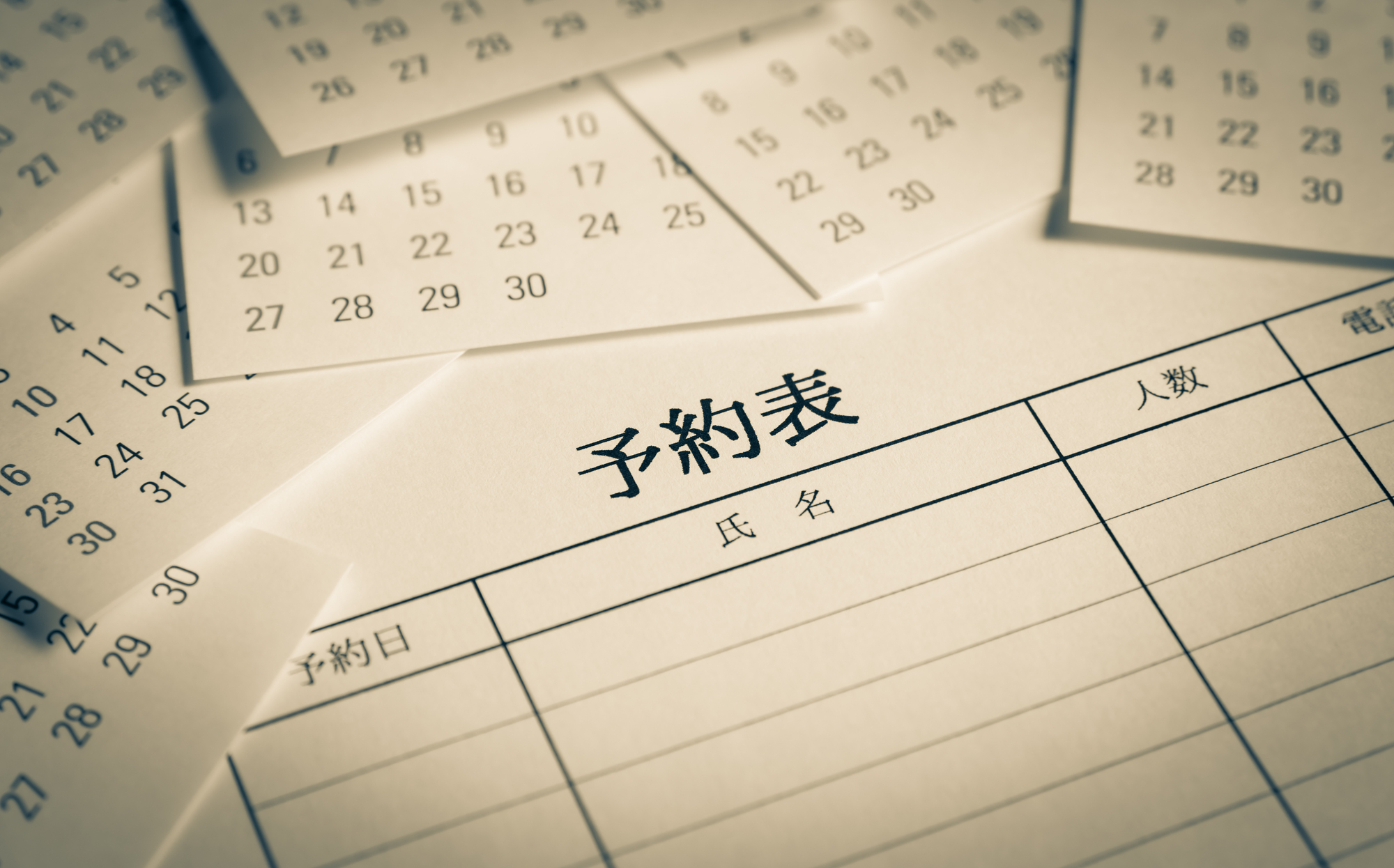 飲食店の予約管理を象徴する予約表とカレンダー。AI予約代行による無断掲載トラブルから店舗を守り、本来の顧客接点を大切にする経営理念をイメージ。正確な予約受付と店舗運営の安定化を目指す、プロの視点による対策マニュアルの象徴的写真。
