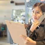 オートリザーブのAI予約電話に対応する飲食店の現場スタッフ。迷惑電話によるオペレーションの混乱を防ぎ、スタッフのストレス軽減と店舗運営の安定化を目指す。現場での電話対応ルールの徹底やスタッフ教育の重要性を象徴するプロフェッショナルな画像。