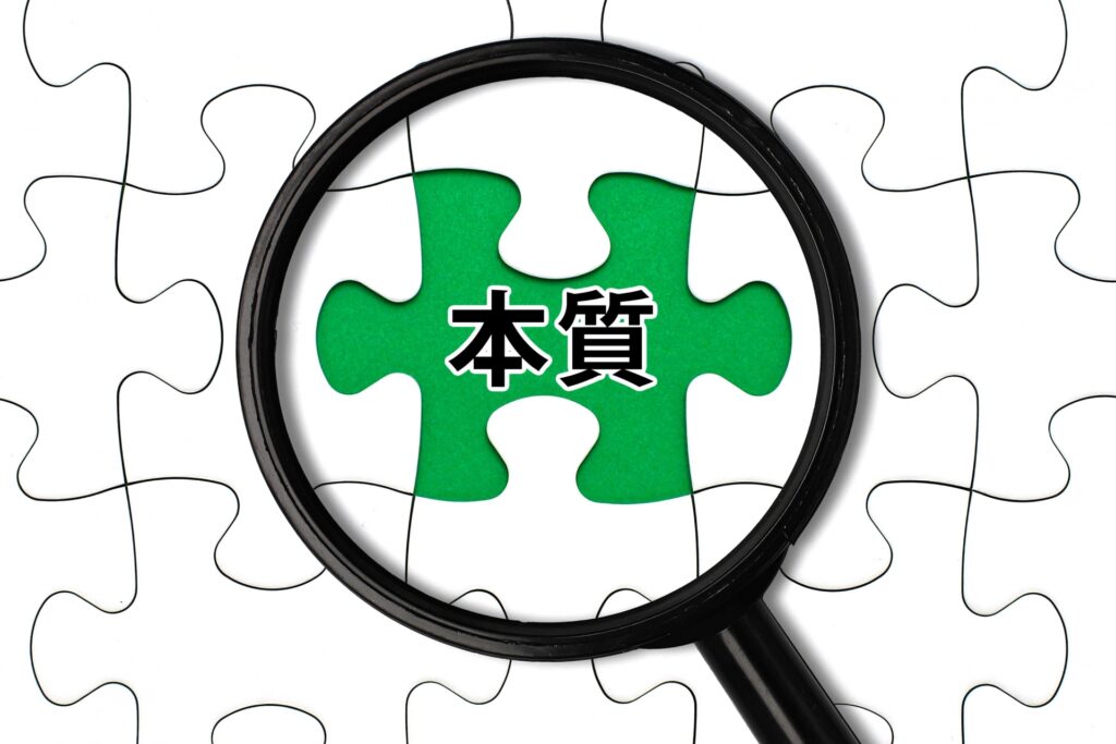 課題解決の「本質」を虫眼鏡で探るイメージ。店舗経営において「誰が正しいか」ではなく「何が正しいか」を追求する経営理念の重要性を強調。柳井正氏の提唱するマニュアルの徹底と再発防止の仕組み化により、持続可能な組織へと活性化させる手法。