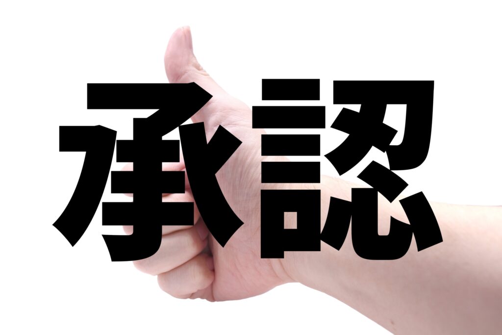 承認の欲求充足を象徴する「承認」の文字とグッドポーズ。岡田卓也氏の「共生」の哲学を現代の店舗運営に応用し、部下の強みを引き出す認める文化を醸成。理念・実務・評価のサイクルを回し、応募者が「働きたい」と感じる店舗イメージの再構築を促す。