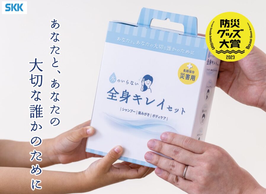 手渡される「水のいらない全身キレイセット」のパッケージ。断水や避難環境下での誤嚥性肺炎を予防する、水のいらない全身ケア用品。介護実績があり、災害時の従業員の健康を守る防災グッズ。