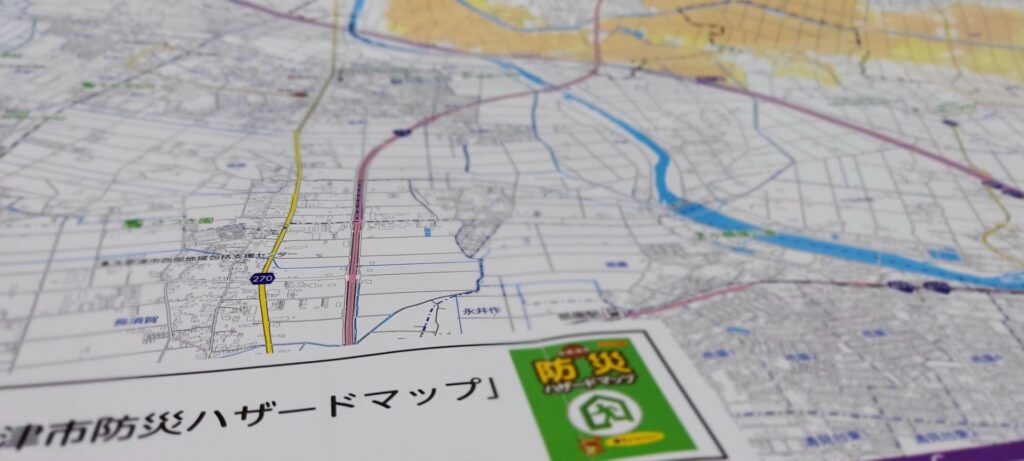 自治体が作成・公開する防災ハザードマップと地域の地図のイメージ。想定最大規模表記の罠を見抜き、店舗周辺の裏山や傾斜地、低地などの危険箇所を自らの足で歩いて点検する現場リスク把握法。