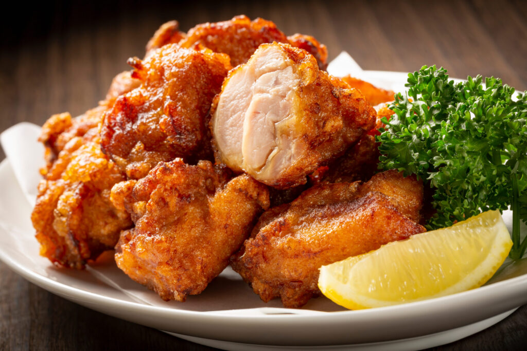 専門料理店や専門居酒屋の主力メニューをイメージした、皿に盛られたジューシーな鶏の唐揚げ(ザンギ)とレモン。安易なディカウント路線に逃げることなく、商品の打ち出し方や見せ方の工夫で適正価格を維持するメニュー戦略の象徴。
