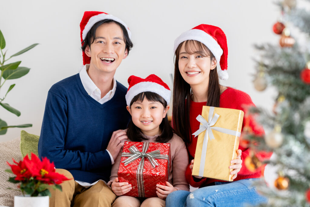クリスマスに笑顔でプレゼントを囲むファミリーの画像。年間販促計画と月別集客カレンダーを活用し、年末商戦や季節催事のファミリー需要を確実に捉え、店舗の売上と客単価を引き上げる飲食・小売・サービス業向け実践マーケティング。