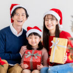 クリスマスに笑顔でプレゼントを囲むファミリーの画像。年間販促計画と月別集客カレンダーを活用し、年末商戦や季節催事のファミリー需要を確実に捉え、店舗の売上と客単価を引き上げる飲食・小売・サービス業向け実践マーケティング。