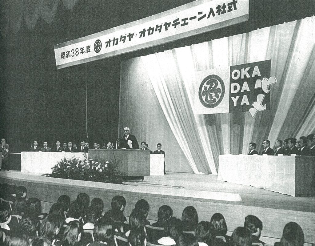 1963年、岡田屋が大卒者の定期採用を本格的にスタートさせた記念すべき年　商業界の倉本長治主幹　入社式で新入社員たちを激励
